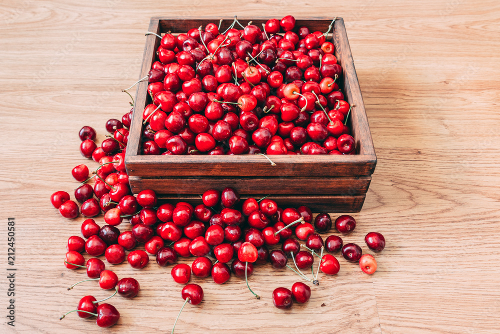 Sweet cherries in the wooden box on the wooden table Sweet cherries in the wooden box on the wooden table
