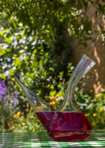 Recipiente para beber Vino tipico de España ( Porron ) con sangria encima de una  mesa a la sombra de verano en el jardin o patio de la casa photo