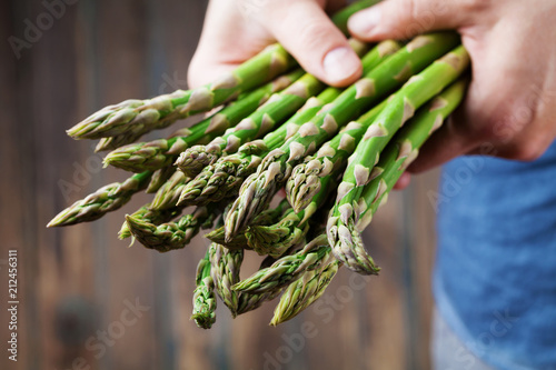 Farmer holding in hands the harvest of fresh green asparagus. Organic and diet vegetables.