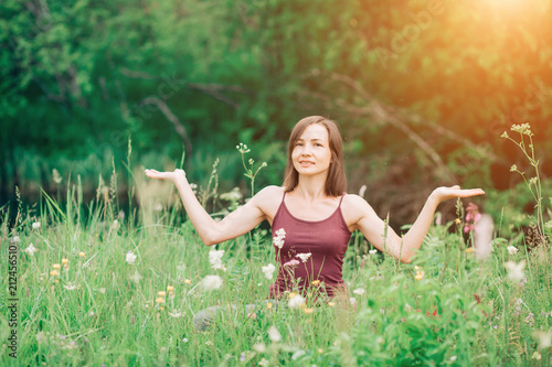 A beautiful woman with open palms with a smile looking at the camera in the clearing