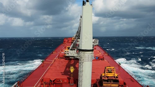 Cargo ship rolling in stormy sea. Huge waves under dramatic sky in South Atlantic.