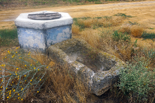 abandoned ancient trough for cattle near a closed well of stone