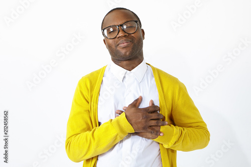 Canvas Print Friendly looking grateful Afro American man keeping hands on his chest, showing sympathy, acknowledgement and gratitude, being in high spirits or flattered