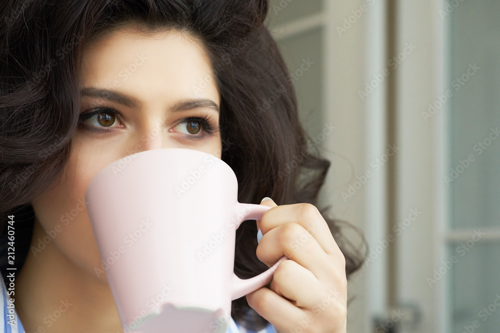 Young girl drinks coffee from a cup slooking into the distance. Young girl drinks coffee from a cup slooking into the distance.