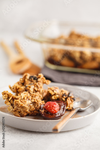 Crumble cake with plum and raspberries in a glass dish, white background. Healthy vegan food concept.