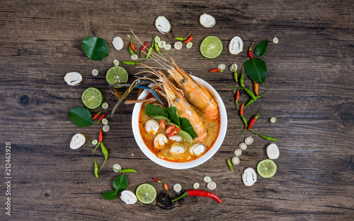 Close up Asian Spicy soup with shrimp in bowl , famous Thai food cuisineม Tom Yum Goong Spicy Sour Soup on wooden table top view