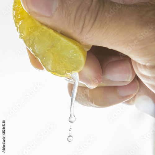 close up Human hand squeezing half of lemon on white background