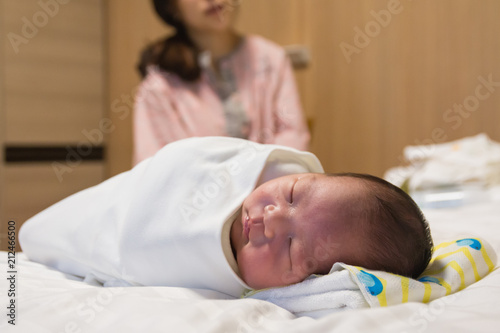 Asian young mother looking at her baby sleeping on the bed
