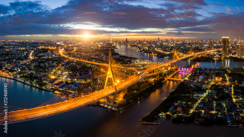 Fototapeta Naklejka Na Ścianę i Meble -  Aerial view of Bhumibol suspension bridge cross over Chao Phraya River in Bangkok city with car on the bridge at sunset sky and clouds in Bangkok Thailand.