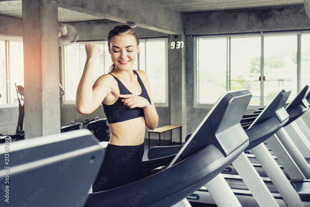 Cute young woman exercising on  treadmill at a gym.Active young woman running on treadmill. smile and funny emotion.