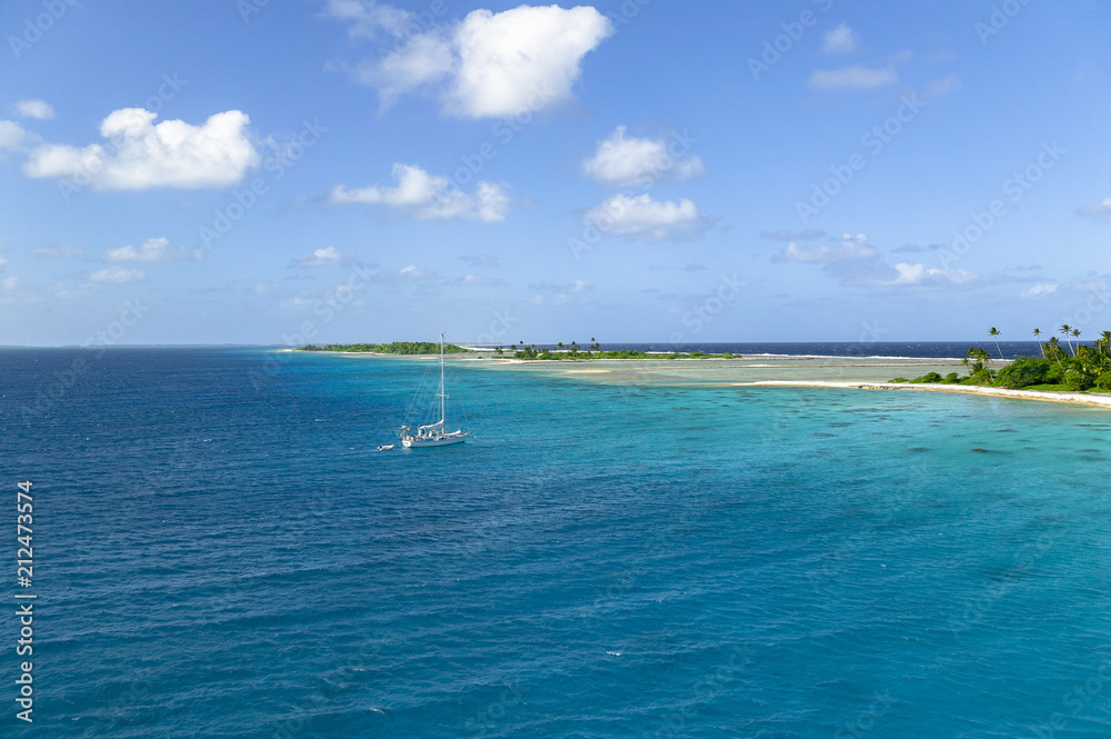 sailing yacht anchoring in the shallow, turquoise lagoon of Fakarava atoll, Tuamotus archipelago, French Polynesia, south pacific