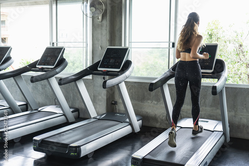 Cute young woman exercising on treadmill at a gym.Active young woman running on treadmill. smile and funny emotion.