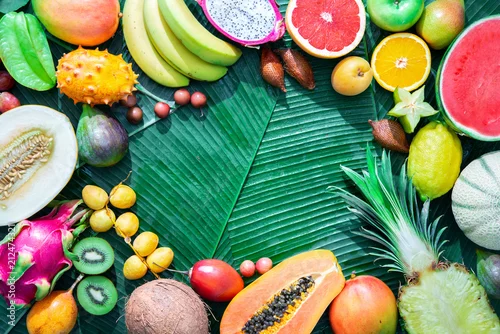 Obraz szeroki asortyment owoców tropikalnych ułożonych na liściach palm