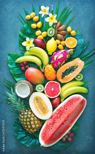Assortment of tropical fruits with palm leaves and exotic flowers
