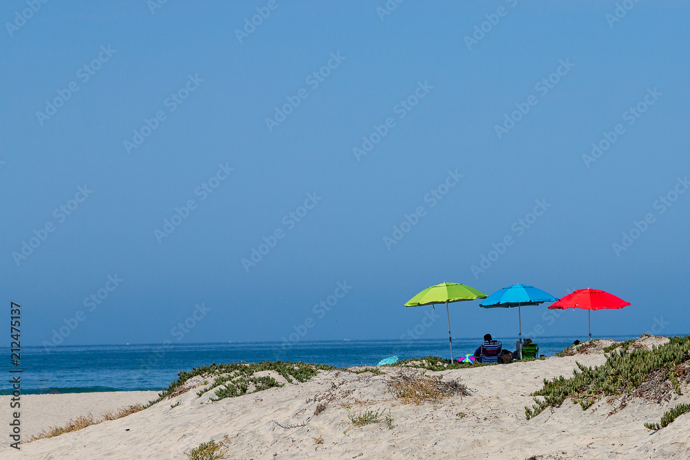 Three colorful beach umbrellas