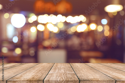 Empty wood table top with blurred light bokeh in night cafe restaurant background