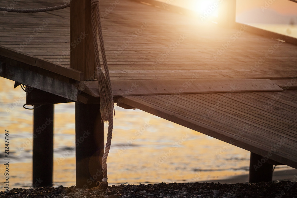 Obraz premium sun shining brightly at the path of thewooden pier with ropes and columns