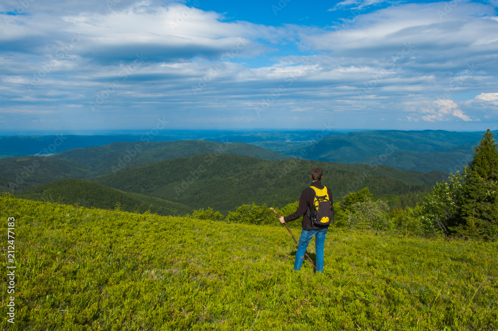 man with a backpack and a stick against the background of the Carpathian mountains landscape