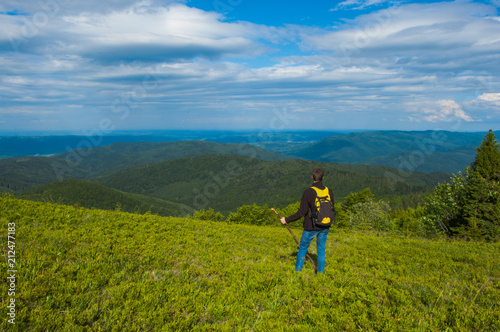 man with a backpack and a stick against the background of the Carpathian mountains landscape