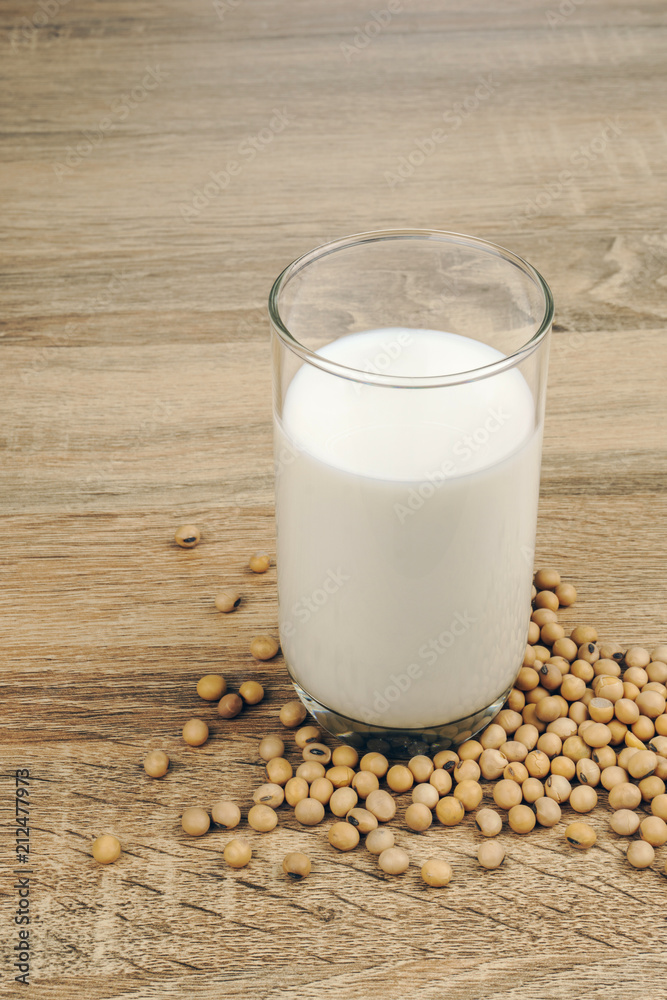 a glass of soy milk and a pile of soybeans on the wooden table. a glass of soy milk and a pile of soybeans on the wooden table.