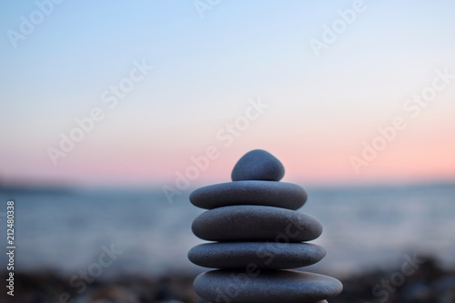 A pile of flat stones on the beach. The sea and sunset in the background