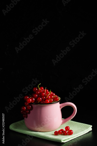 Redcurrant pile (ribes rubrum) pink cup green napkin dark background