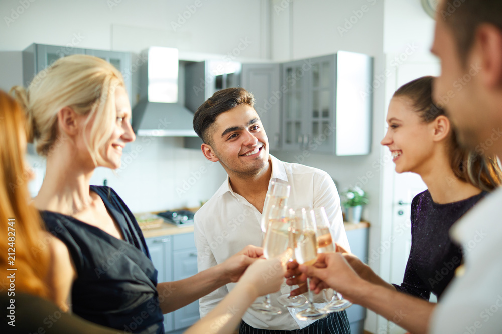 Happy guy and several girls clinking with flutes of champagne while enjoying home party Happy guy and several girls clinking with flutes of champagne while enjoying home party