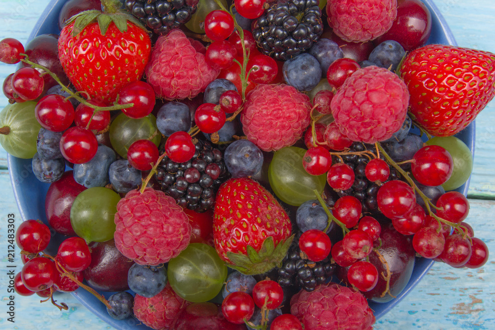 Various summer Fresh berries in a bowl on rustic wooden table. Antioxidants, detox diet, organic fruits. Top view Various summer Fresh berries in a bowl on rustic wooden table. Antioxidants, detox diet, organic fruits. Top view