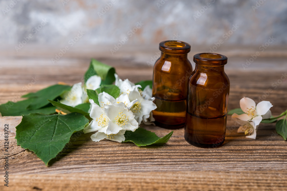Essential jasmine oil with jasmine flowers  on wooden background.