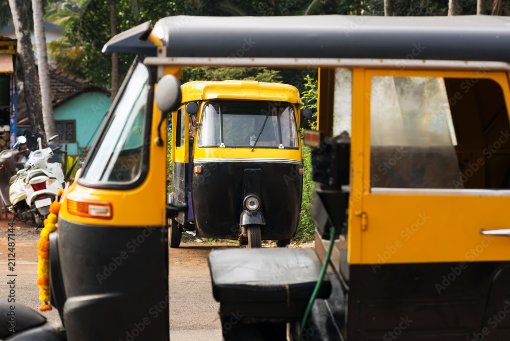 A vehicle, yellow-black auto rickshaw, for the transportation of tourists to Asian countries.