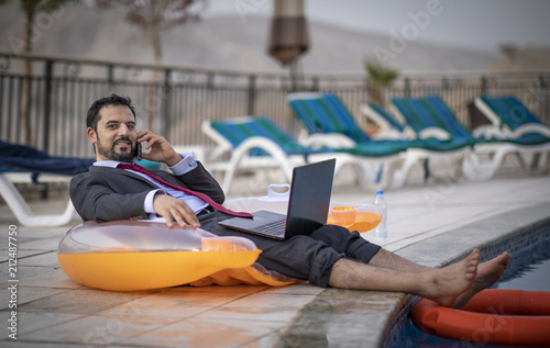 Foto middle aged arab man by a pool working  in his business suit