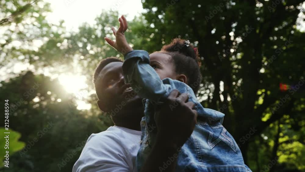 Portrait african father hugging his daughter play holds on hands twists spending holiday together in park family affection smile happy slow motion child summer man kid sun girl parenting outdoors