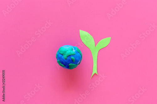 Fototapeta Naklejka Na Ścianę i Meble -  Planet, ecology. plastiline symbol of planet Earth globe and plant coutout on pink background top view copy space