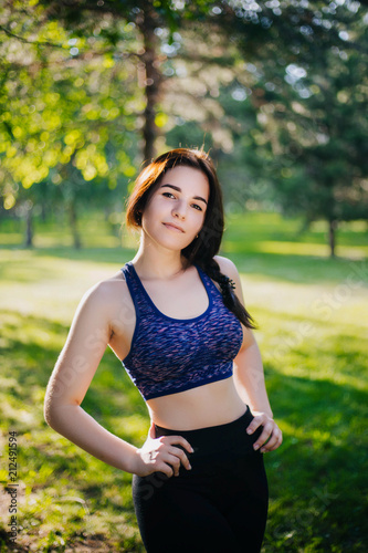 A beautiful girl in the park is engaged in sports. A model with clean skin and oboyatelnoy ulvbkoy in sportswear. Open-air trainings.