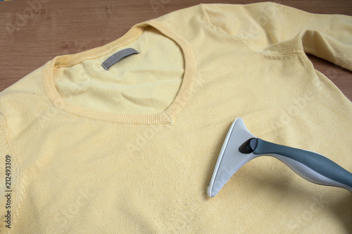 Fuzz remover on yellow fabric with fuzz balls.