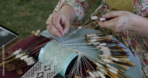 Historic handmade lace weaving woman. Bobbin lace is a textile made by braiding and twisting lengths of thread by hand. Hobby for highly homemade delicate clothing and decoration and art.