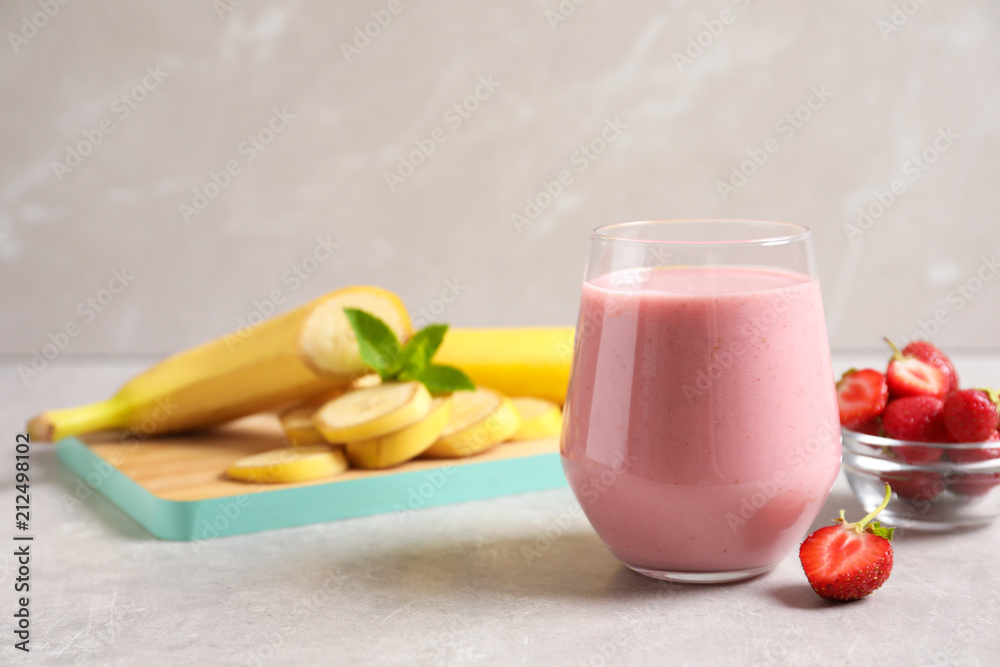 Glass with tasty strawberry smoothie on table