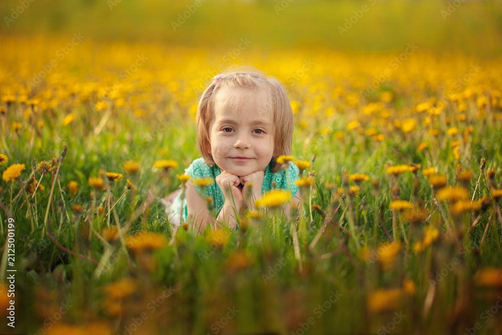 Cute little girl lying on the yellow dandelion meadow in summer day. Cute little girl lying on the yellow dandelion meadow in summer day.