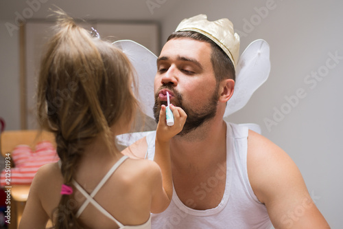 Little daughter and father have fun, dressing in princess costume, daddy makeup