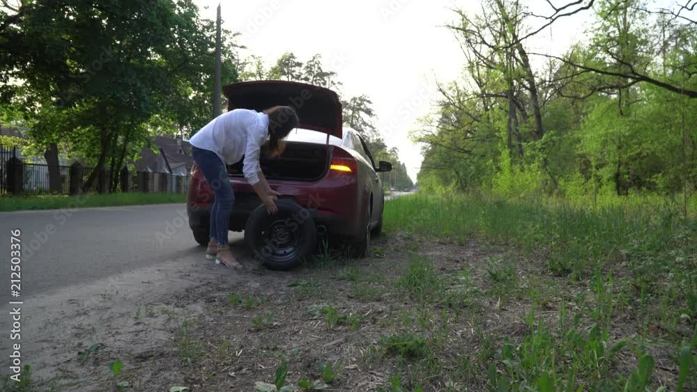 Pregnant woman changing a punctured tire at the car. repair of cars on the road. Pregnant woman changing a punctured tire at the car. repair of cars on the road.