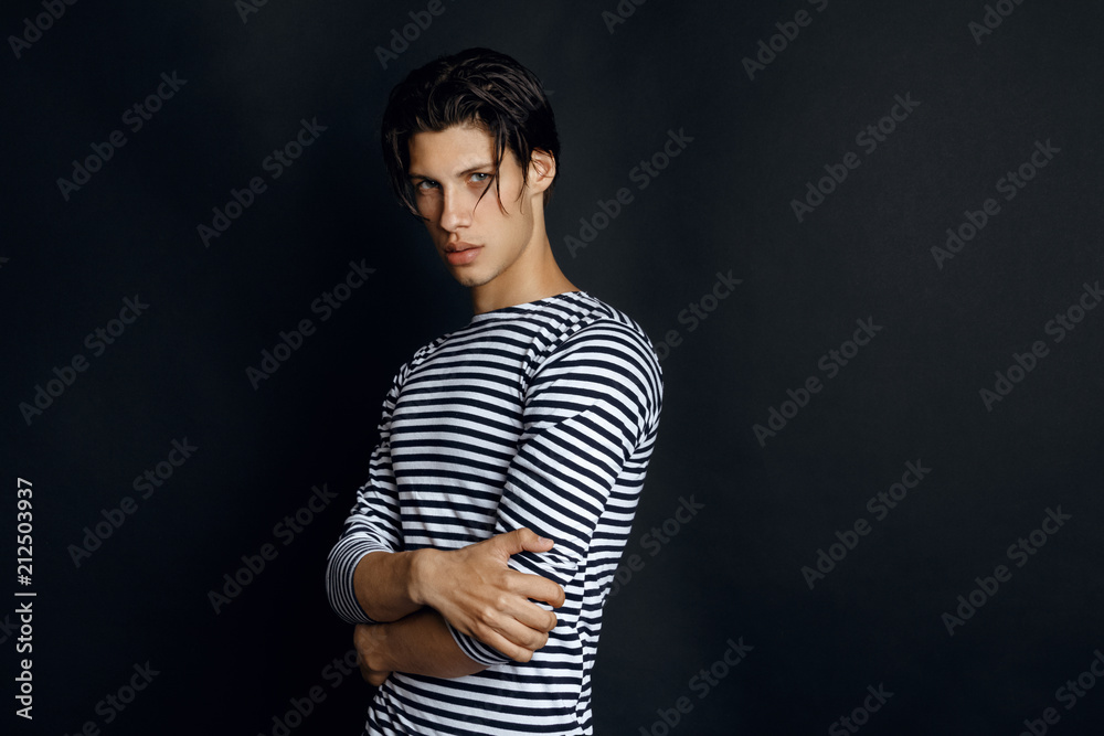 Sexy male model in sailors black and white shirt on black background