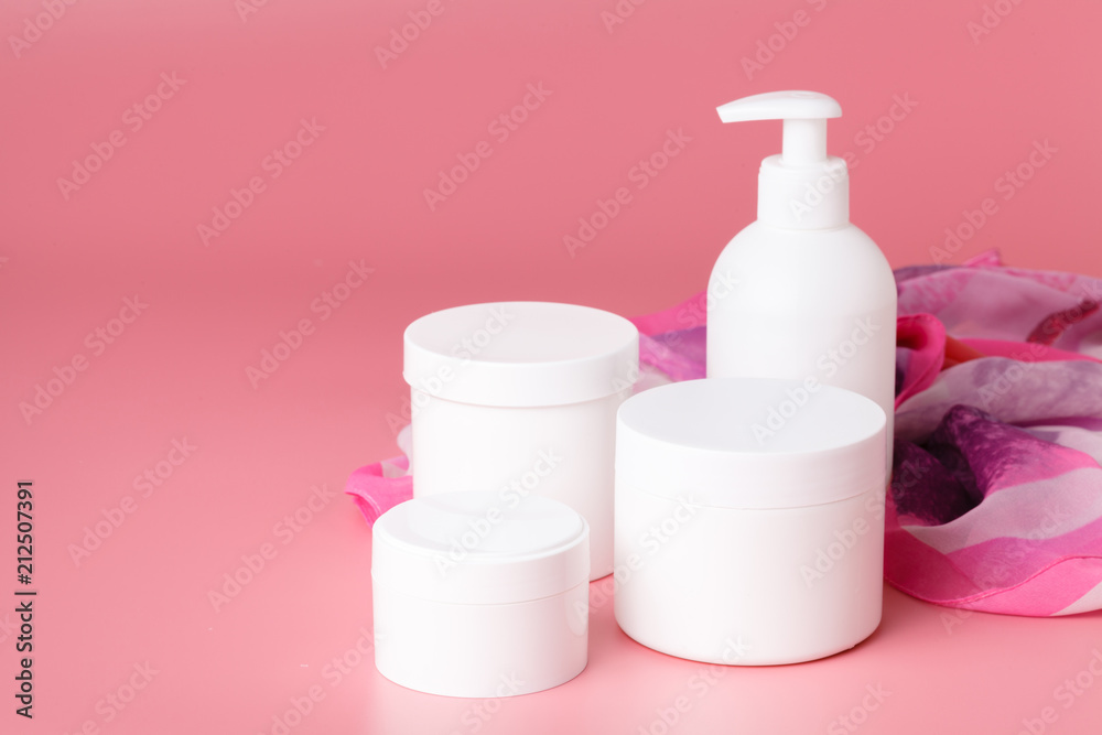 Cosmetic cream container and pink flowers on pink plaint background Cosmetic cream container and pink flowers on pink plaint background