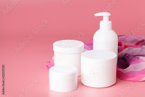 Cosmetic cream container and pink flowers on pink plaint  background