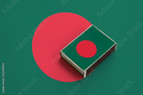 Bangladesh flag  is pictured on a matchbox that lies on a large flag photo