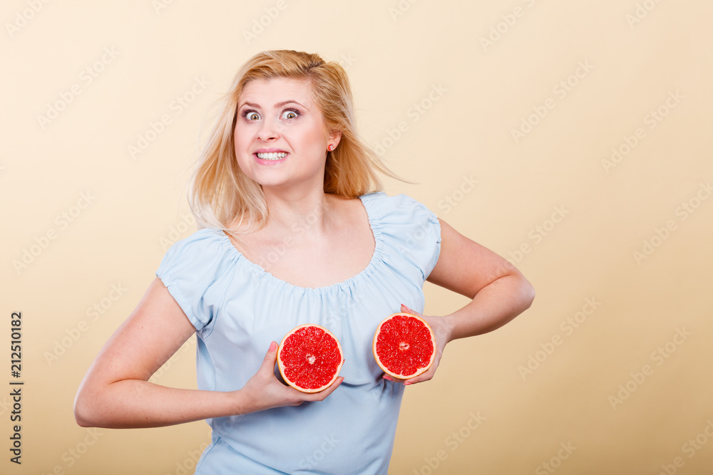 Woman holding red grapefruit on breast Woman holding red grapefruit on breast