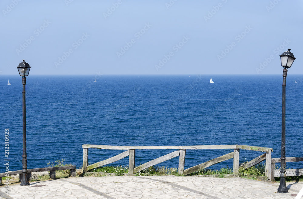 View of the sea with a fence and two lampposts