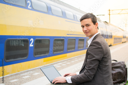 Young business man working on a laptop at a train station in the Netherlands