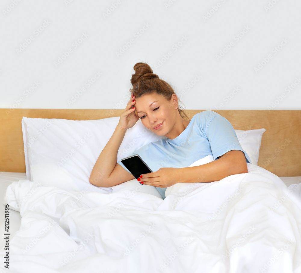 Young woman using smart phone .Woman resting and sitting on a bed Young woman using smart phone .Woman resting and sitting on a bed
