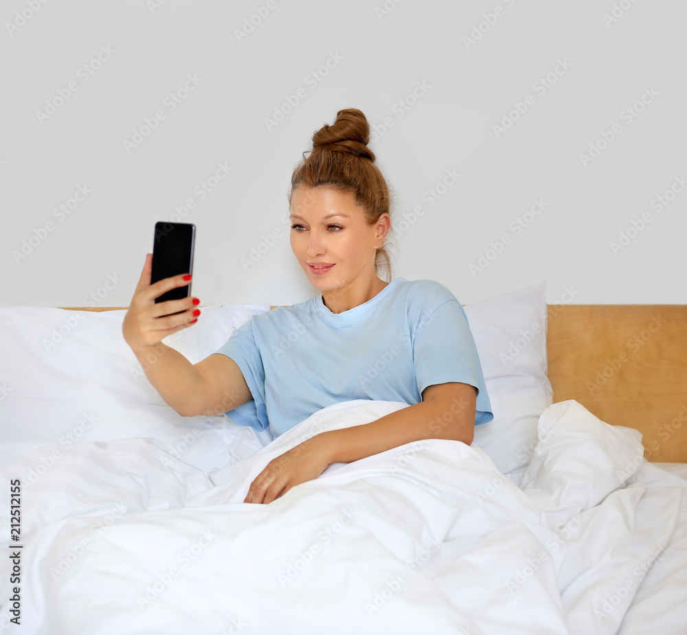 Woman relaxing on her bed,using smarthone