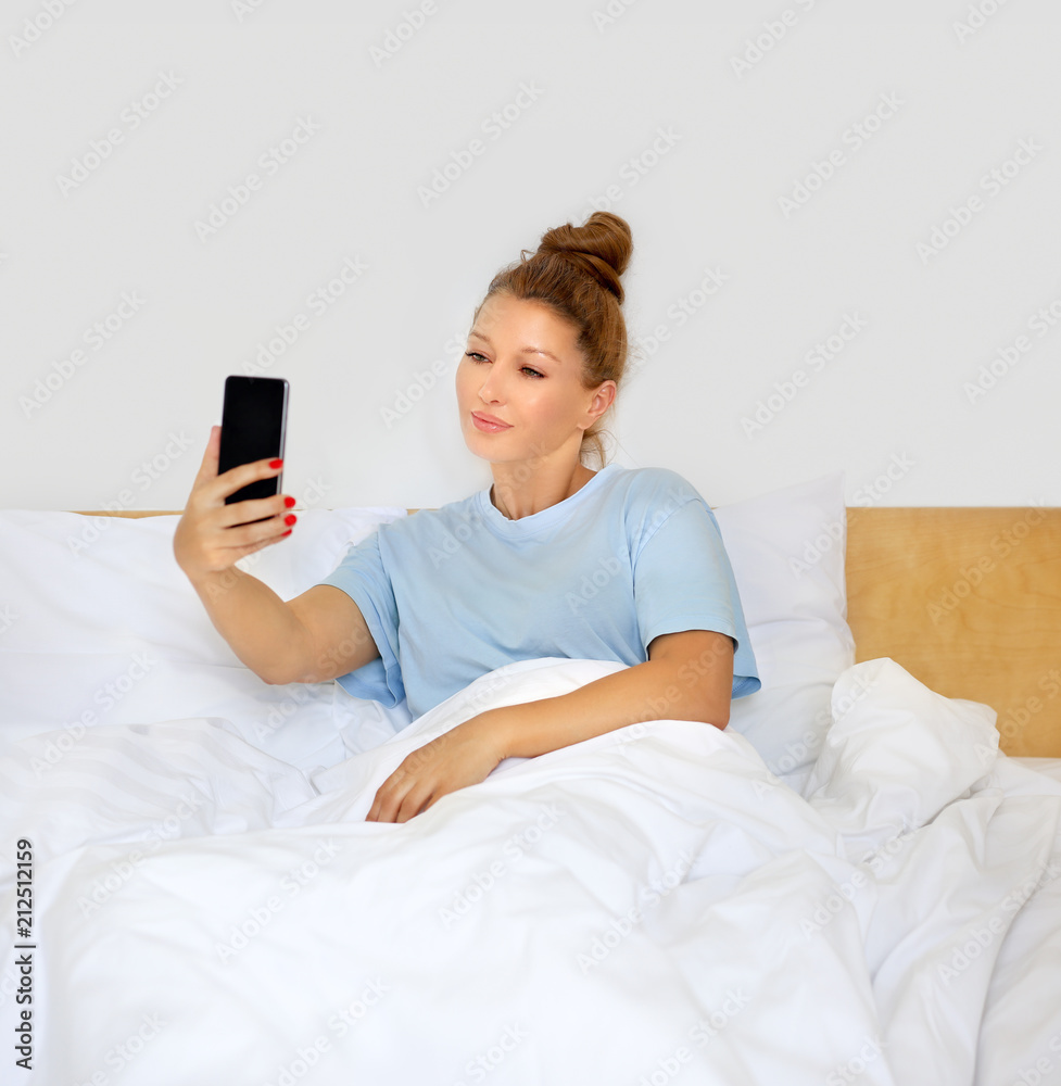 Woman relaxing on her bed,using smarthone